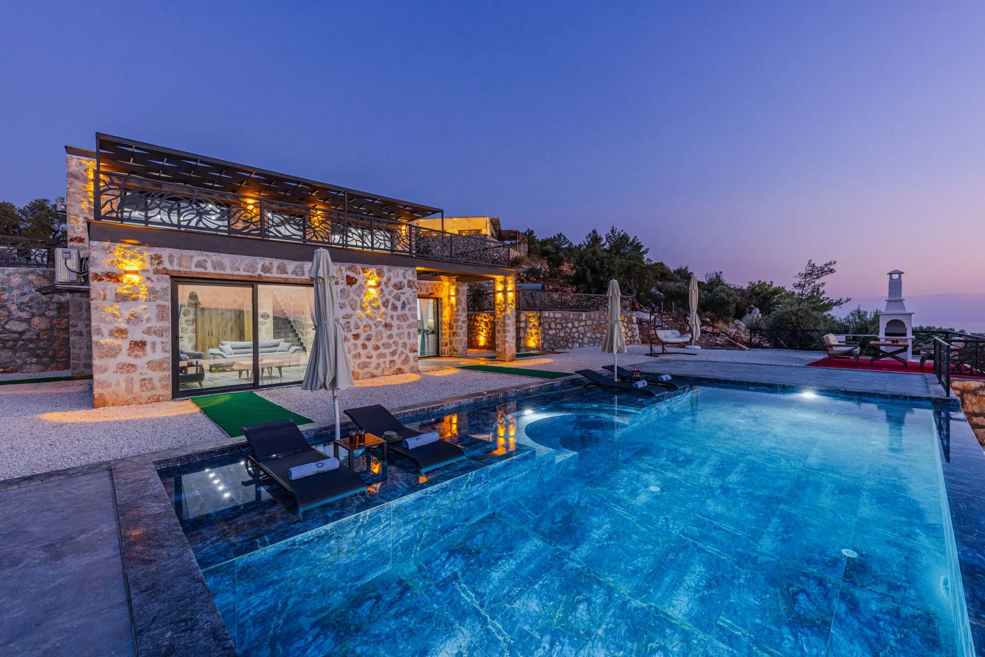 A stone private residence and illuminated pool at blue hour, illustrating the AUREL Residences property studio concept